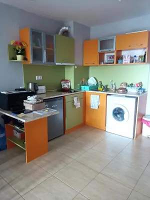 a kitchen with orange and green cabinets and a washing machine at Two room apartment in Etara 3, Sveti Vlas in Sveti Vlas