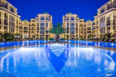 a large building with a palm tree in front of it at Апартамент под наем С208 в Афродита Гарденс in Sunny Beach