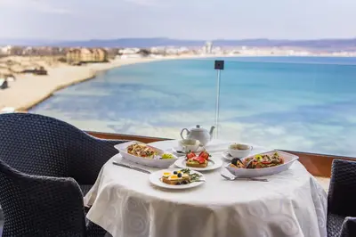 a table with three plates of food on it with a view of the beach at Paradiso Dreams Hotel in Nesebar