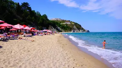 a group of people laying on a beach with umbrellas at Byala Cliff Sea View Suite in Byala