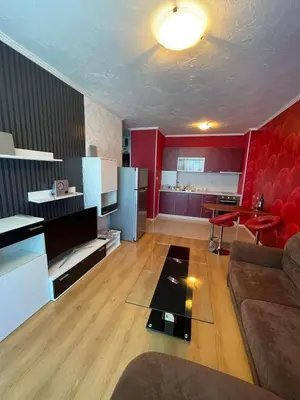 a living room with a couch and a kitchen with red walls at Apart hotel Gallery A in Sunny Beach