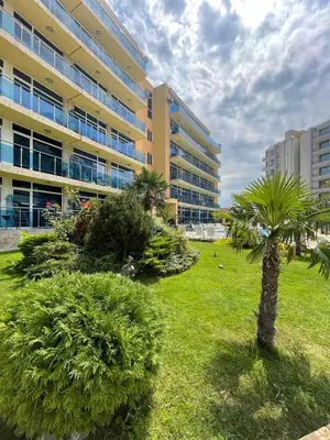 a building with a palm tree in front of a park at Apart hotel Gallery A in Sunny Beach