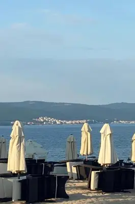 a group of tables with umbrellas on the beach at Joy Apartment Sunny Beach in Sunny Beach