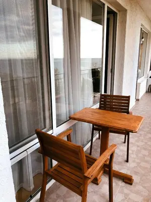 a wooden table and two chairs sitting on a balcony at Beautiful apartment right by the sea, Sveti Vlas in Sveti Vlas