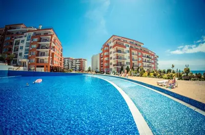 a large blue swimming pool next to some buildings at Beautiful apartment right by the sea, Sveti Vlas in Sveti Vlas