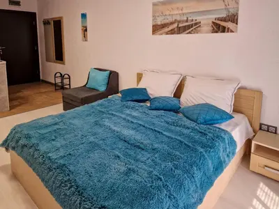 a bedroom with a large bed with a blue blanket at Апарткомплекс Амара Слънчев Бряг Студио 13 in Sunny Beach