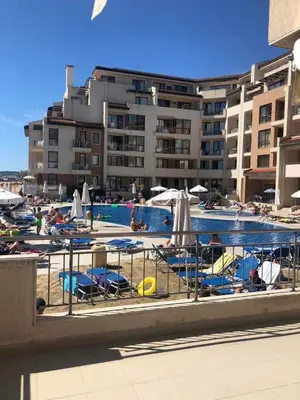 a pool with chairs and umbrellas next to a building at Obzor Beach Resort Beachfront in Obzor