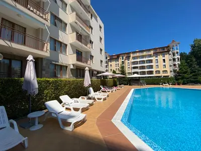 a swimming pool with chairs and umbrellas next to a building at SUMMER BREEZE 110 Cozi Studio in Sunny Beach
