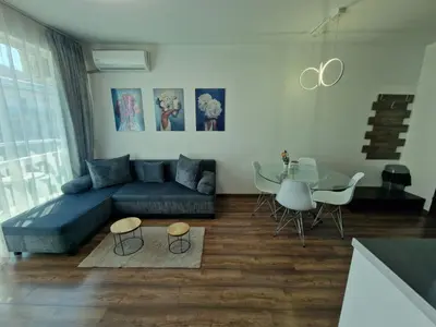 a living room with a blue couch and a glass table at Апартамент СаMи in Burgas City