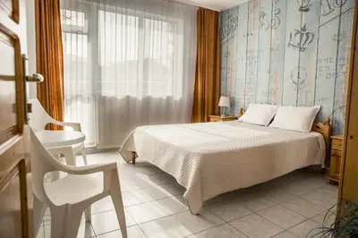 a bedroom with a bed and a chair and a window at Panorama Chantall-izby,apartmány s výhľadom na more in Ravda