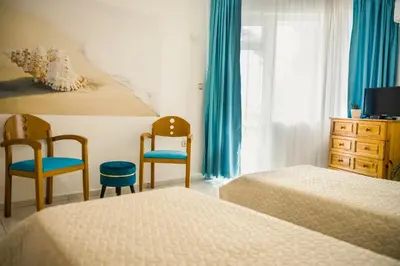 a hotel room with two beds and two chairs at Panorama Chantall-izby,apartmány s výhľadom na more in Ravda