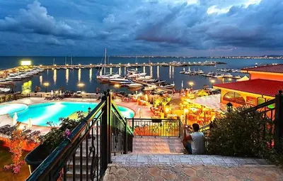 a man sitting on a balcony looking at a marina at Royal Palm Studio with Seaview in Sveti Vlas