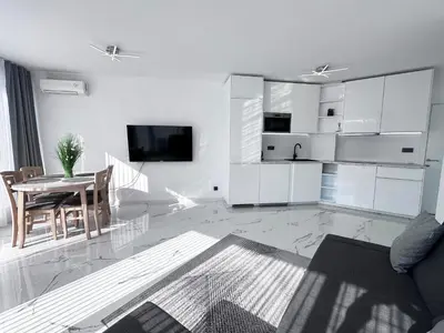 a white living room with a table and a tv at Admiral Plaza Apartment , Large swimming pool , 5 min walking to the beach in Sunny Beach
