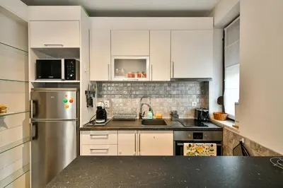 a kitchen with white cabinets and a stainless steel refrigerator at Varna beach flat 1 in Varna City