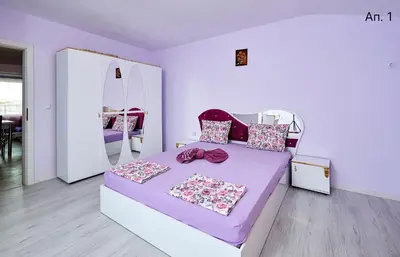 a bedroom with a purple bed and a mirror at Апартаменти Боряна in Pomorie