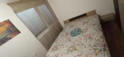 a bedroom with a bed with a floral bedspread at Апартамент с две спални. in Varna City