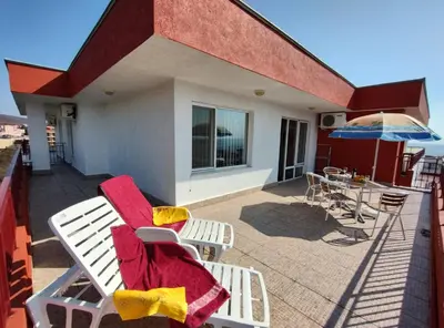 a deck with chairs and an umbrella and a table at Apartament Panorama - BastetBS in Sveti Vlas