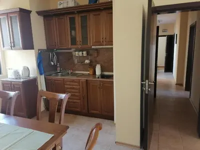 a kitchen with wooden cabinets and a table and chairs at Созопол Дриймс FSM Апартамент in Sozopol
