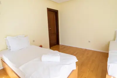 a bedroom with a bed with white sheets and a wooden floor at Central flat with Monster living room in Varna City