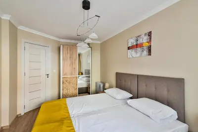 a bedroom with a bed with white sheets and yellow blanket at Top location flats in Varna in Varna City
