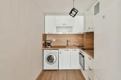 a kitchen with white cabinets and a washer and dryer at Top location flats in Varna in Varna City