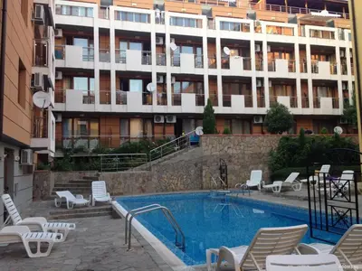 a swimming pool with chairs and a large building at Святой Влас, комплекс Sea Breeze in Sveti Vlas