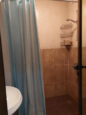 a shower with a blue shower curtain next to a sink at Святой Влас, комплекс Sea Breeze in Sveti Vlas