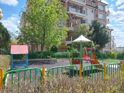 a playground in front of a tall building at Святой Влас, комплекс Sea Breeze in Sveti Vlas