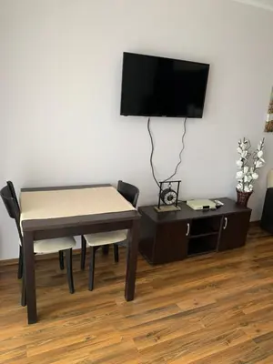 a living room with a table and a tv on a wall at Студио Нели- Созополистайл Клуб in Sozopol
