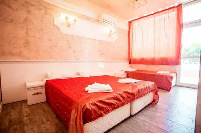 a bedroom with two beds with red sheets and a window at BIATO APARTMENTS - ALL INCLUSIVE in Sunny Beach