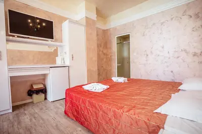 a bedroom with a bed with red sheets and a tv at BIATO APARTMENTS - ALL INCLUSIVE in Sunny Beach