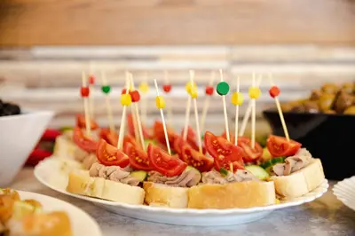 a sandwich with tomatoes and meat on a plate with tooth picks at BIATO APARTMENTS - ALL INCLUSIVE in Sunny Beach