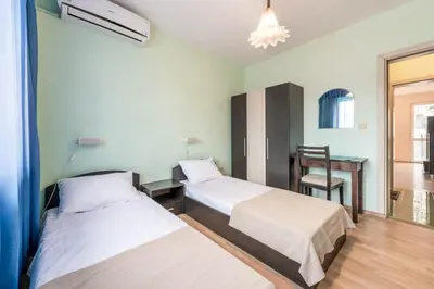 two beds in a room with a desk and a chair at Sea&Park Apartment in Varna City