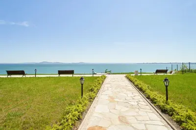 a walkway with benches and the ocean in the background at M1 Pool and Beach View Apartment in Burgas City