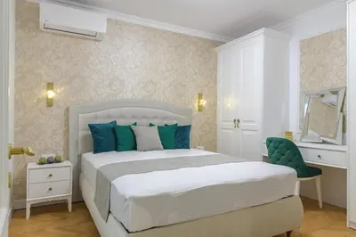 a bedroom with a white bed and a green chair at ЛУКС НА МОРЕ Luxury apartment in downtown with garage in Varna City