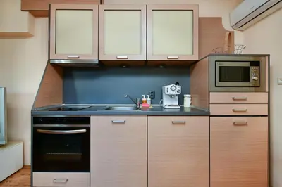 a kitchen with wooden cabinets and a stove top oven at Budget 1BR flat downtown Varna in Varna City