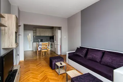 a living room with a purple couch and a kitchen at Super Central flat in Varna in Varna City