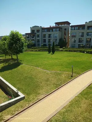 a park with a building in the background and a walkway at Апартамент Orange в местност Каваци, Созопол in Sozopol