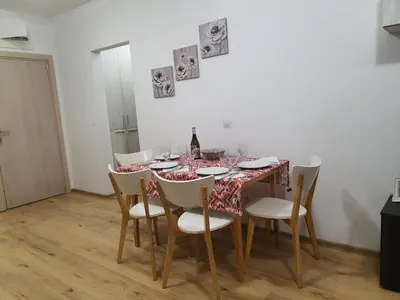 a dining room table with chairs and a bottle of wine at Apartament Topalov in Burgas City