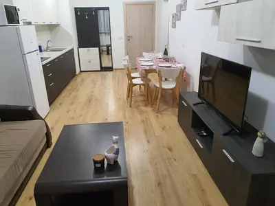 a small living room with a table and a kitchen at Apartament Topalov in Burgas City