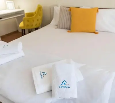 a hotel room with a white bed with towels on it at Studio Porto in Varna City
