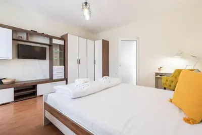 a white bedroom with a large bed and a tv at Studio Porto in Varna City