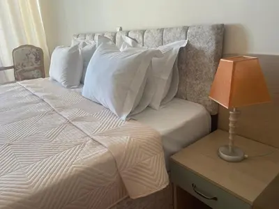 a bed with white pillows and a table with a lamp at Grand Hotel Nirvana - All Inclusive & Free Beach Access in Sunny Beach