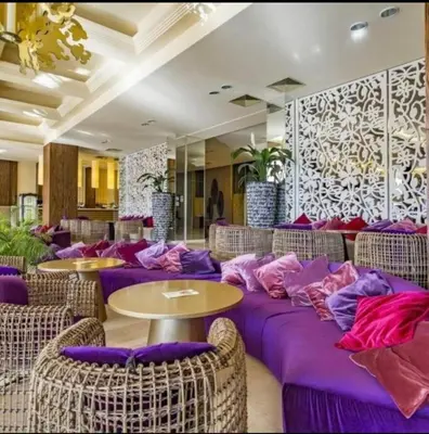 a restaurant with purple pillows and tables and chairs at Reina Apart Barcelo Beach in Sunny Beach