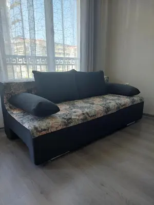 a couch with two pillows sitting in front of a window at Nereya Studio in Pomorie