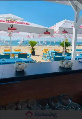 a table with chairs and umbrellas on a beach at Bayview Family Garden Studio A1 in Burgas City