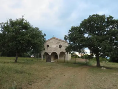 an old stone building in a field with two trees at Villa Entre in Emona