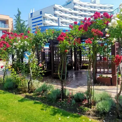 a garden with flowers in front of a building at Trakia Plaza Apartament Sunny Beach in Sunny Beach