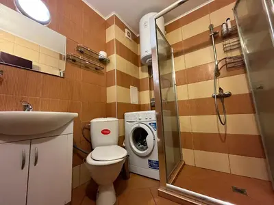 a bathroom with a toilet and a washing machine at Vqra Sarafovo in Burgas City