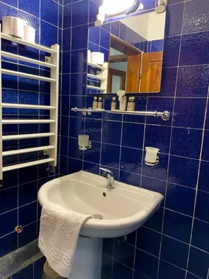 a blue tiled bathroom with a sink and a mirror at Apart Zefira 2 Rooms in Varna City